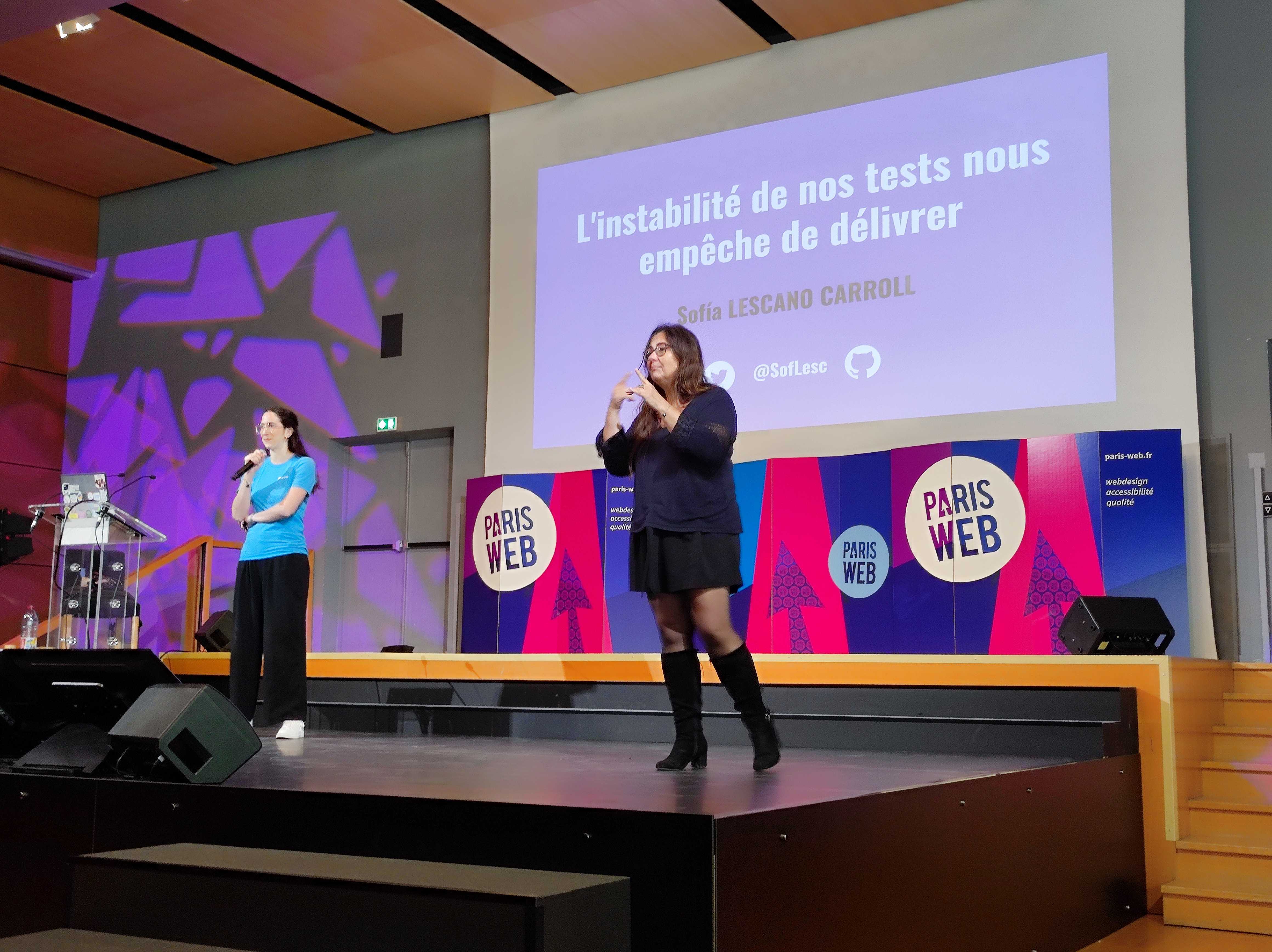 Sofia Lescano Carroll en train de présenter "L’instabilité de nos tests nous empêche de délivrer". Une interprète LSF est sur la scène.